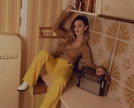 Georgia Box is a Music Gateway independent pop artist, shown sitting on a kitchen worktop listening to the radio